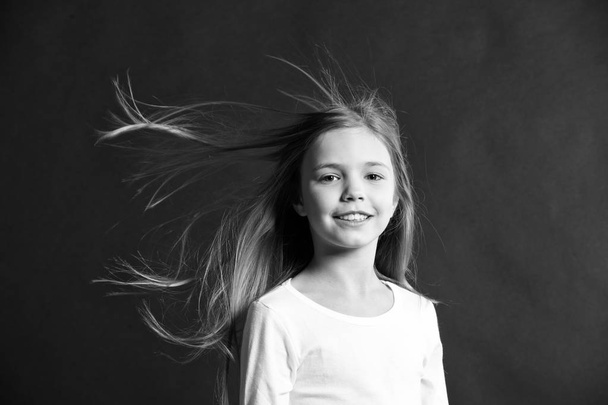 Natural beauty. Girl kid long hair flying in air, black background. Child with natural beautiful healthy hair. Quick tips for healthy hair. Growing hair recommendation. Extremely effective product - Foto, afbeelding