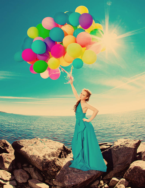 balon gökyüzüne karşı sahilde elinde ve güneşin uzun elbiseli kadın lüks moda şık - Fotoğraf, Görsel