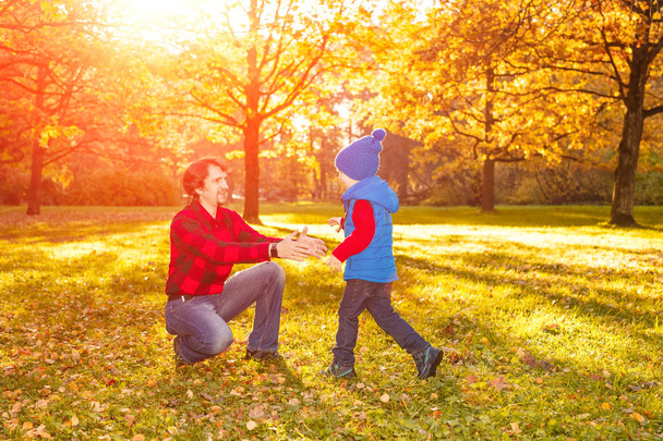 Der Vater geht mit seinem Sohn im Herbstpark spazieren. Ein Kind und ein Mann im Wald amüsieren sich bei einem Spaziergang. Familie verbringt Zeit in der Natur - Foto, Bild