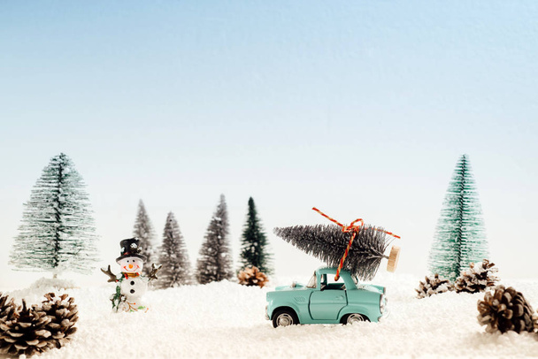 Voiture jouet portant l'arbre de Noël dans un paysage enneigé et hivernal
  - Photo, image