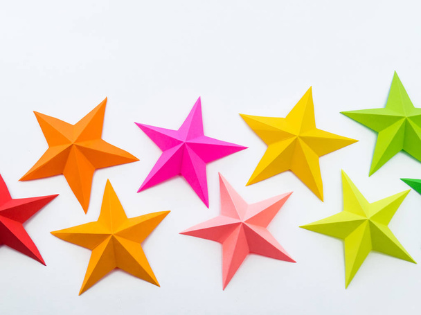 A star made of rainbow-colored paper. Festive decor starry sky. White background. Favorite hobby. Creativity with children. - Zdjęcie, obraz