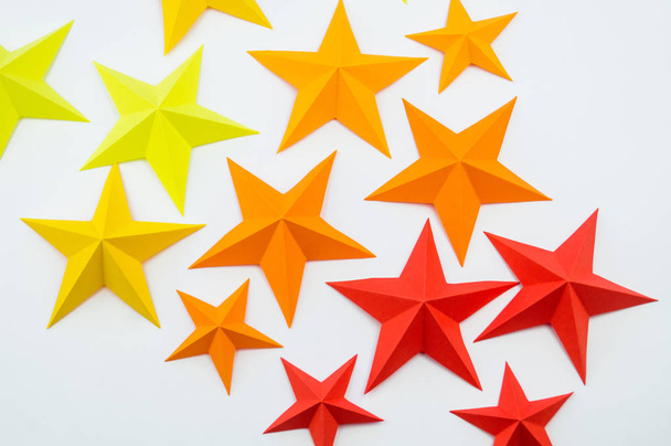 A star made of paper the color of red orange yellow. Festive decor starry sky. White background. Favorite hobby. Creativity with children. - Foto, Imagen