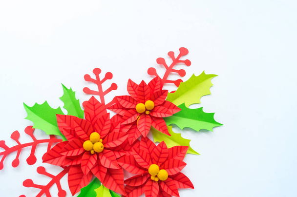 Paper flower poinsettia and leaves of holly. Christmas wreath. White background. Colors are green, red, yellow. - Photo, image