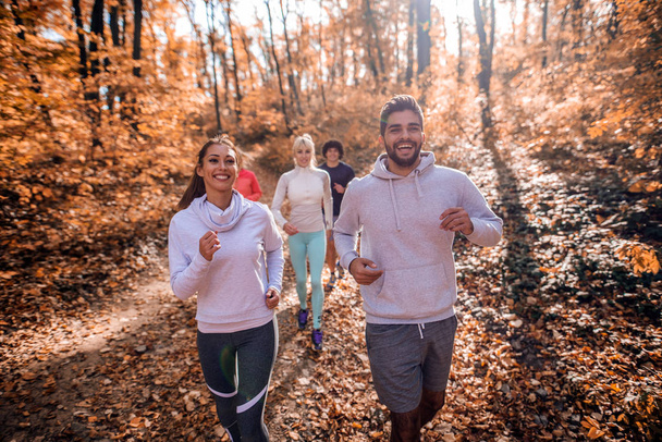Järjestäytynyt pieni ryhmä ihmisiä juoksee metsässä syksyllä
. - Valokuva, kuva