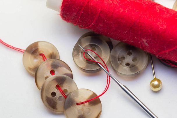 Agulha com fio e botão isolado em branco, bordado e conceito de alfaiataria botões de costura, agulhas e pinos
. - Foto, Imagem