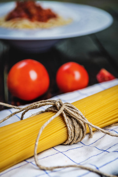 イタリアの生パスタ スパゲッティとダークウッドのテーブルのトマト - 写真・画像