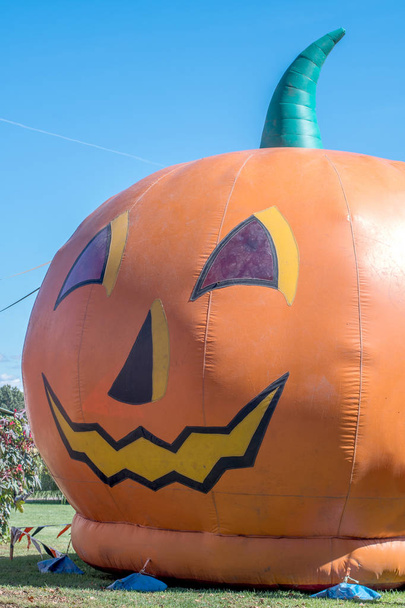 giant inflatable bouncy house is in the shape of a smiling orange pumpkin - Photo, image