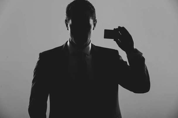 silhouette of man holding business or bank card - Foto, Bild