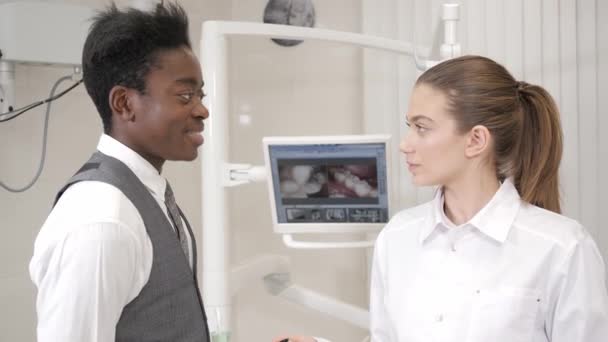Krásná žena zubař doktor. Mladý Američan Afričana pacient mužského pohlaví. Lékařství, zdravotnictví, stomatologie koncept. zubní lékař provádí kontroly a uzavírá - Záběry, video