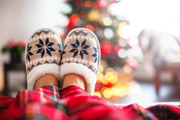 Legs in slippers on Christmas tree background - Φωτογραφία, εικόνα
