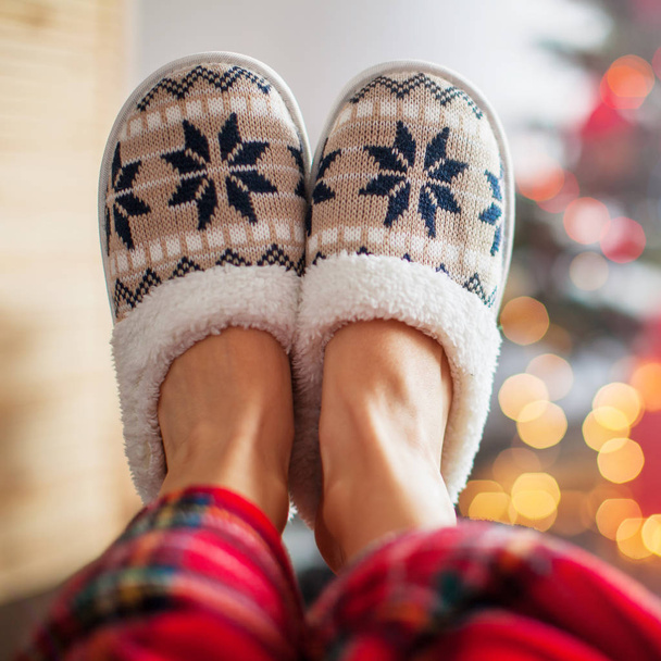 Legs in slippers on Christmas tree background - Фото, изображение