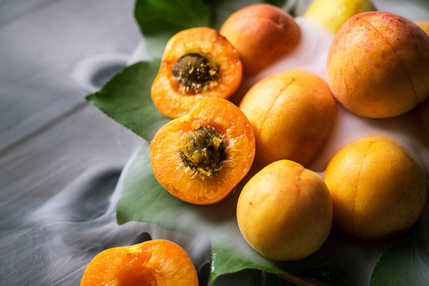 apricots with leaves on a plate and low fog on a black wooden background - Fotografie, Obrázek