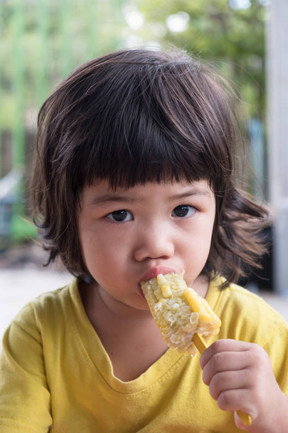 Ázsiai lány rusztikus stílusban tartsuk érett kukorica. Vegetáriánus termék. - Fotó, kép