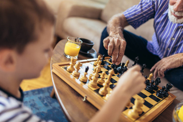 Young boy is playing chess with his grandfather at home. - Photo, Image