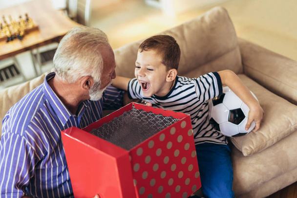 Красивый дедушка преподносит подарок счастливому внуку
 - Фото, изображение