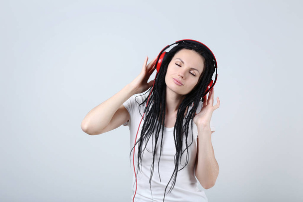 Cute young woman with headphones on grey background - Foto, immagini