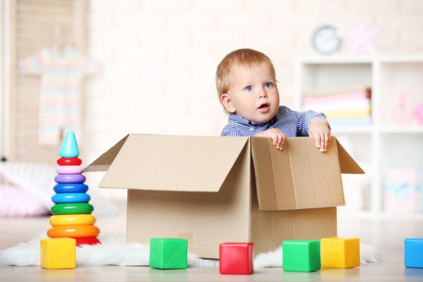 Baby boy sitting in cardboard box at home - 写真・画像