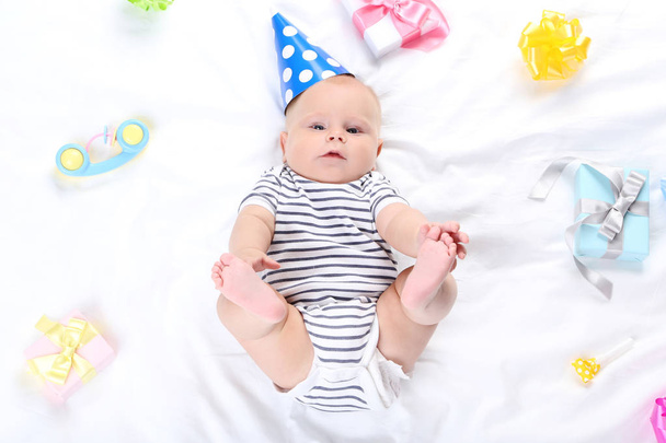 Baby boy with toys and gift boxes lying on white bed - Foto, Bild