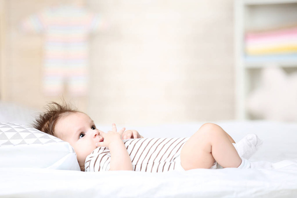 Cute baby lying with pillow on white bed - Photo, image