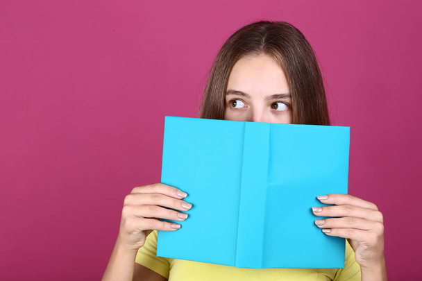 Young girl holding book on pink background - Φωτογραφία, εικόνα