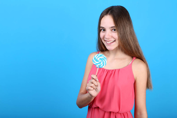 Νεαρό κορίτσι με γλειφιτζούρι σε μπλε φόντο - Φωτογραφία, εικόνα