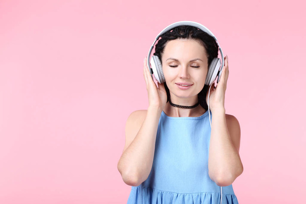 Young woman with headphones on pink background - Foto, Imagen