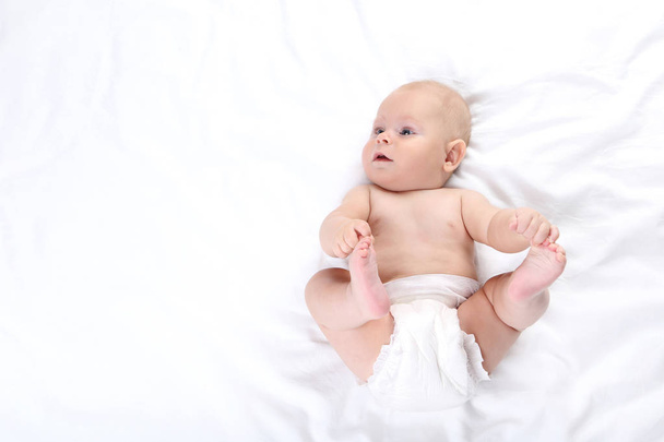 Little boy in diaper lying on white bed - Φωτογραφία, εικόνα
