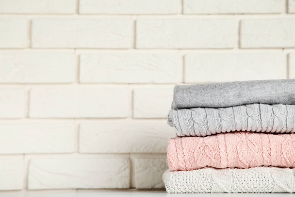 Stack of folded sweaters on brick wall background - Foto, afbeelding