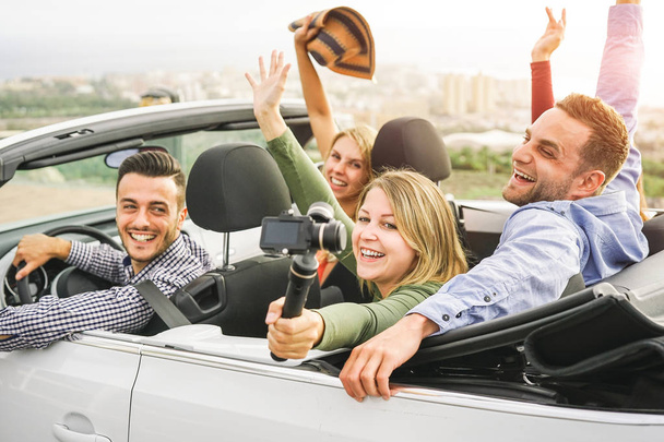 Happy vrienden nemen van foto's met selfie stok camera in converteerbare auto in vakantie - jongeren plezier in cabriolet auto tijdens hun reis - vriendschap, busreizen, levensstijl jeugdconcept - Foto, afbeelding