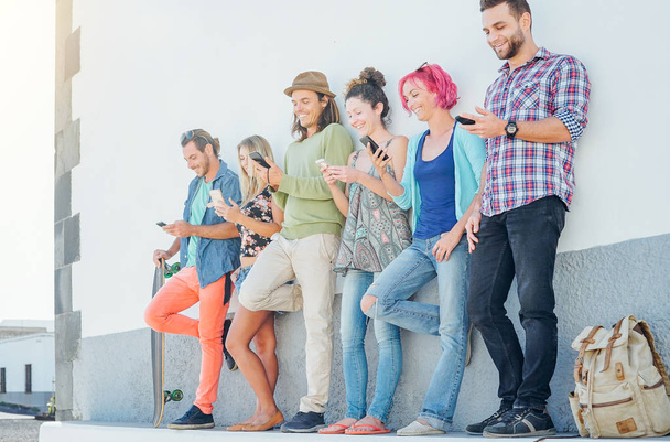 Giovani che guardano sui loro telefoni cellulari intelligenti appoggiati a un muro - Generazione dipendente dalle nuove tecnologie - Concetto di dipendenza dei giovani dalle tendenze dei social network
 - Foto, immagini