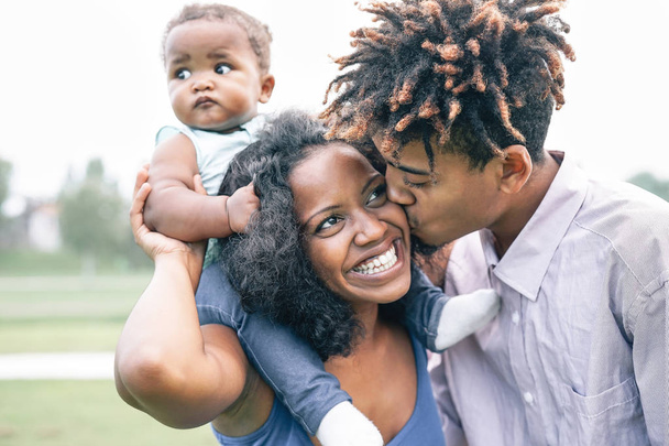 glückliche schwarze Familie, die sich im Park im Freien amüsiert - Mutter und Vater mit ihrer Tochter genießen die gemeinsame Zeit an einem Wochenendtag - Konzept Liebe und Glück - Foto, Bild