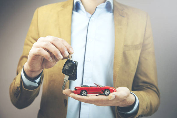 young business man holding red car toy and key - Photo, Image