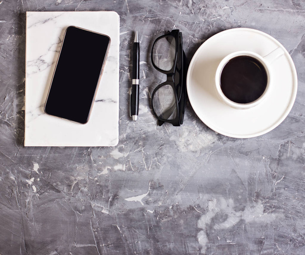 desk workspace with Notepad, diary, glasses, mobile phone, coffee, succulent on cement background. Business still life. Business concept. flat lay, top view - Fotó, kép