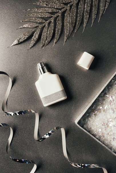vue du dessus du flacon de parfum, rubans argentés et feuilles décoratives brillantes sur gris
 - Photo, image