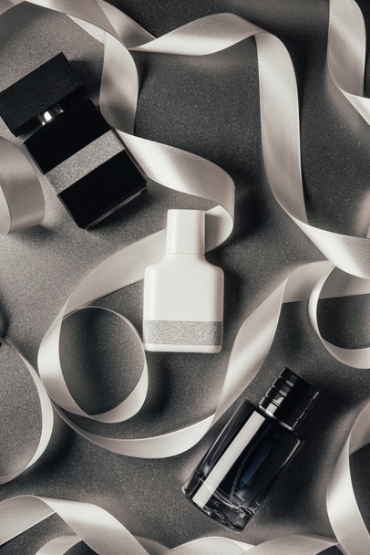 vue de dessus des parfums en bouteille et rubans blancs sur gris
   - Photo, image