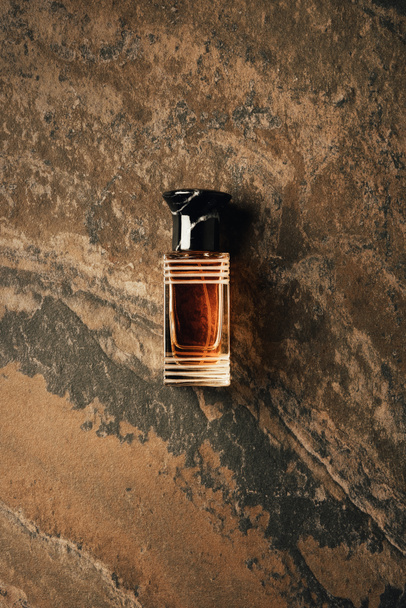 вид зверху пляшки парфумів на коричневій вивітрюваній поверхні
  - Фото, зображення
