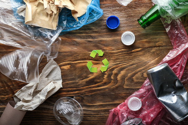 Different garbage with symbol of recycling on wooden background. Ecology concept - Photo, Image