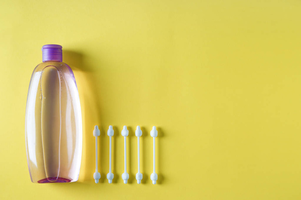 Botella de champú para bebés con hisopos de algodón sobre fondo de color
 - Foto, Imagen