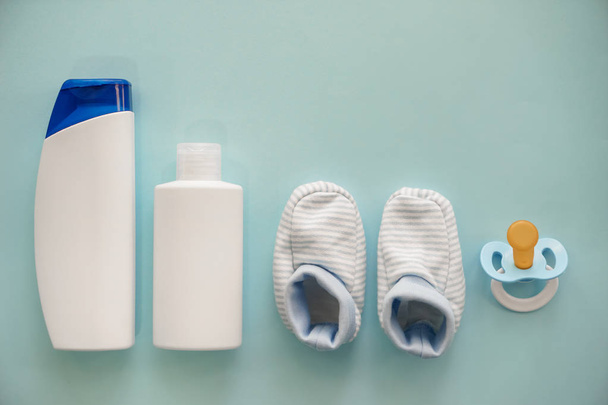 Pacifier with shoes and cosmetics for baby on color background - Φωτογραφία, εικόνα