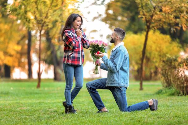 Νεαρός άνδρας που προτείνει στην αγαπημένη του στο πάρκο φθινόπωρο - Φωτογραφία, εικόνα