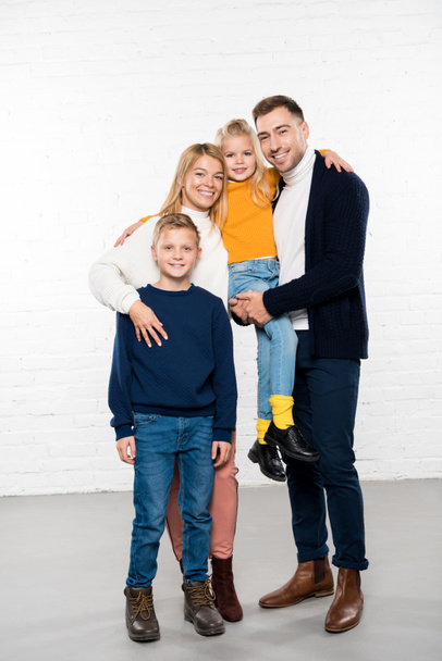 smiling family in casual clothes hugging and looking at camera on white background - 写真・画像