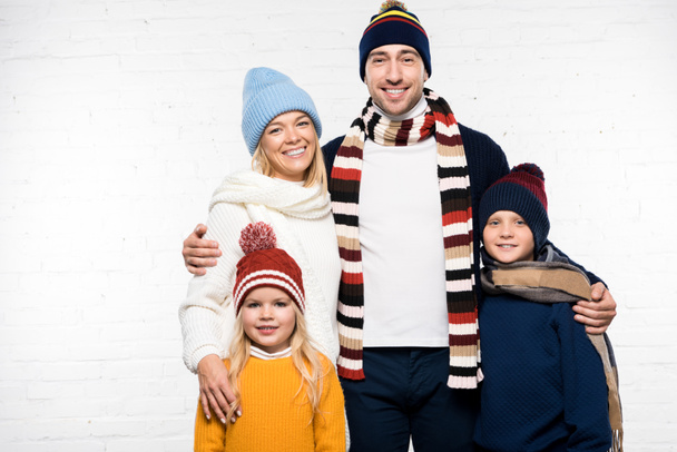 familia sonriente en ropa de invierno abrazando y mirando a la cámara sobre fondo blanco
 - Foto, Imagen