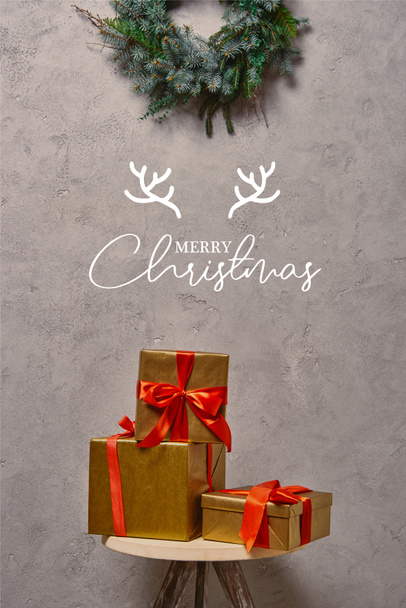 caixas de presente de Natal dourado na cadeira sob a grinalda de abeto no quarto com letras "Feliz Natal" com chifres de veado
 - Foto, Imagem