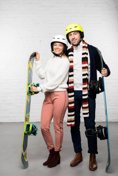 Aviomies ja vaimo lumilaudat ja lumilauta kypärät valmiina talvilomalle
 - Valokuva, kuva