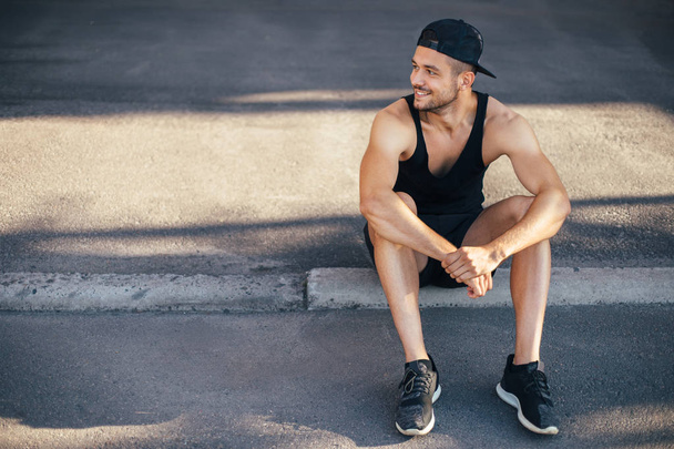 Hadsome sporty man relax sitting on street. Copy space - Foto, Imagen