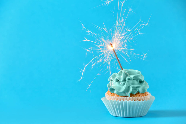 leckere Cupcake mit Wunderkerze auf farbigem Hintergrund - Foto, Bild