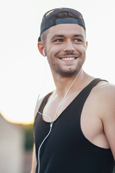 Handsome smiling man in headphones listening to music outdoors - Foto, Imagem