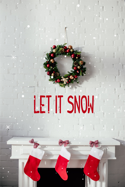 kandalló karácsony harisnya és fenyő koszorú tégla falon a buborék "hagyjuk, hogy a hó" felirat - Fotó, kép