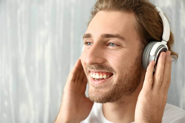Young man listening to music on grey background - Zdjęcie, obraz