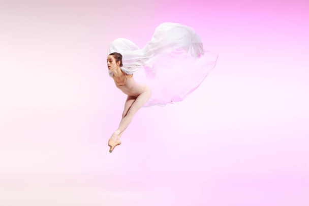 Ballerina. Young graceful female ballet dancer dancing over pink studio. Beauty of classic ballet. - 写真・画像
